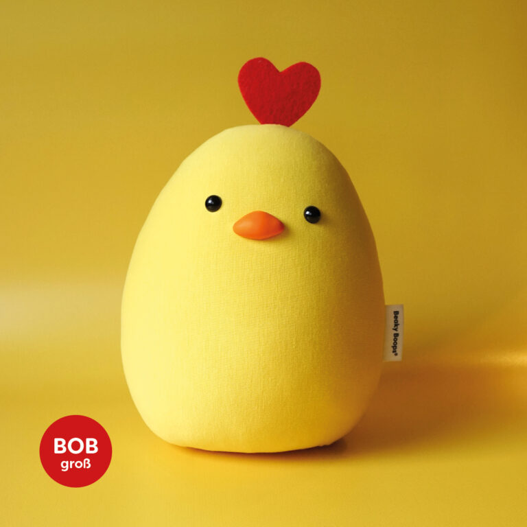 Gelbes Stofftier namens Bob mit kleinen schwarzen Knopfaugen und orangenem Schnabel, ein Produkt der Marke Beaky Boops, Küken mit Herz